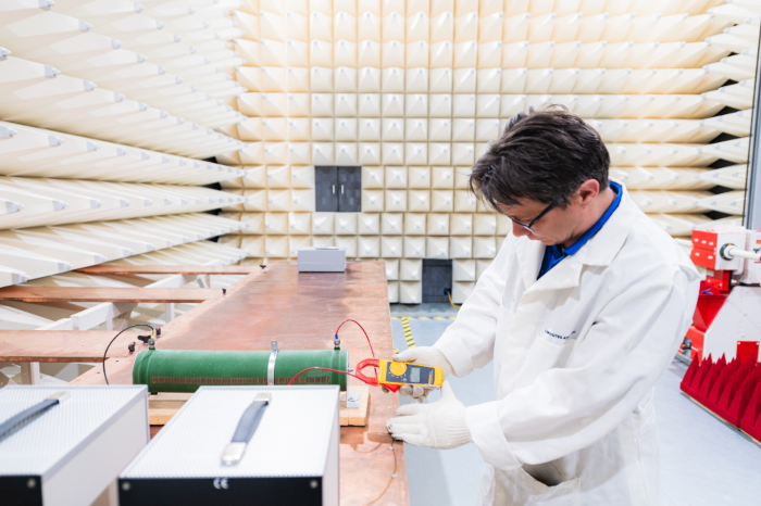 2.	Technician performing EMI testing inside an RF anechoic chamber using measurement equipment on a test bench.